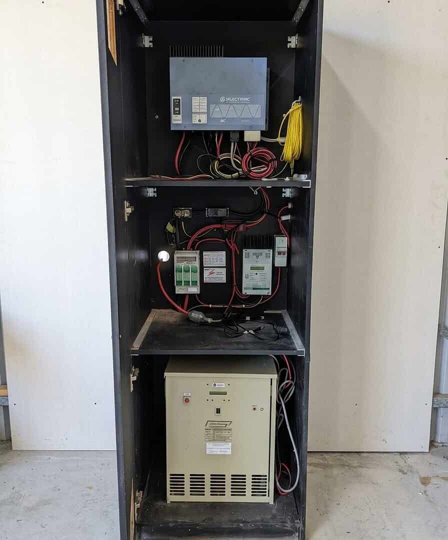Older off-grid solar system in Kempsey, NSW, showing a Selectronic inverter and legacy components mounted inside a tall cabinet.