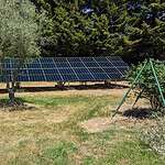 Large ground-mounted solar panel array with 100up service vehicle on rural Victorian property with trees in background