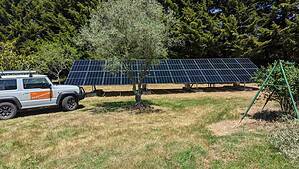 Large ground-mounted solar panel array with 100up service vehicle on rural Victorian property with trees in background