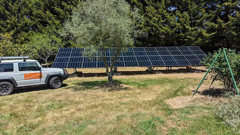 Large ground-mounted solar panel array with 100up service vehicle on rural Victorian property with trees in background