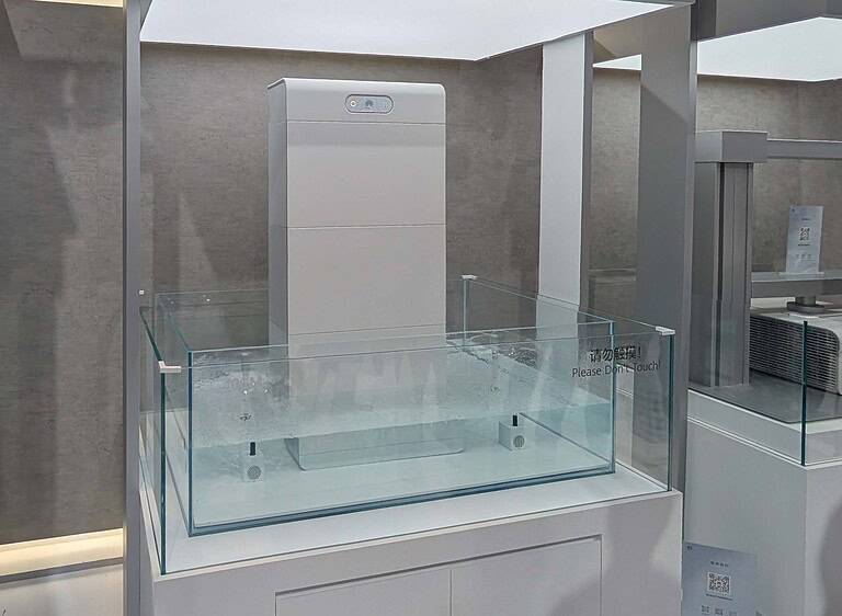White battery unit displayed in glass case in modern showroom with Chinese and English signage