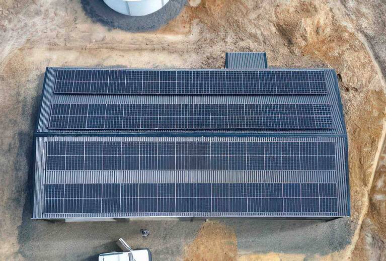 Aerial view of extensive ground-mounted solar panel array with multiple rows of panels on cleared rural land