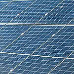 Large solar panel installation showing multiple rows of photovoltaic panels with visible mounting frames and connections
