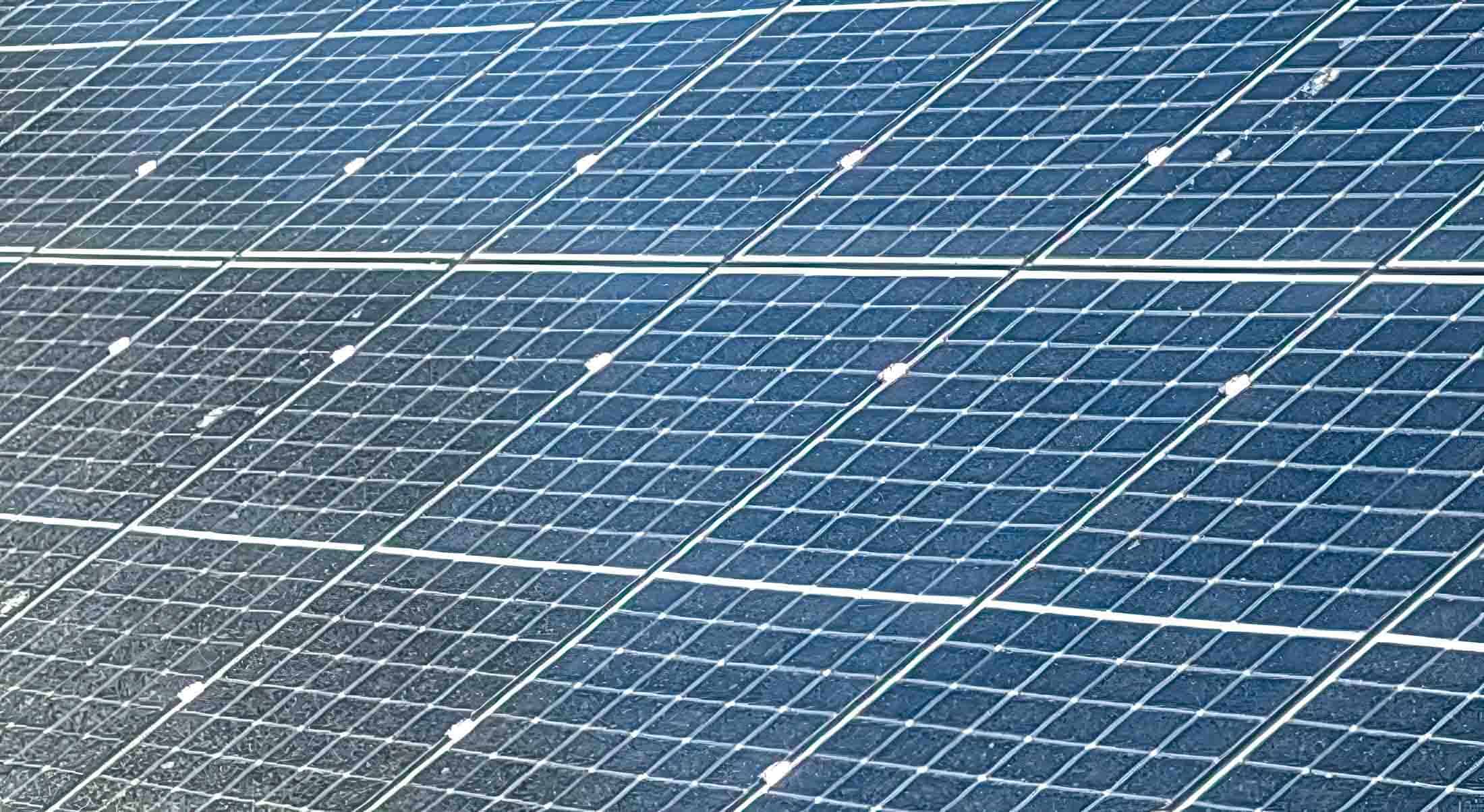 Large solar panel installation showing multiple rows of photovoltaic panels with visible mounting frames and connections
