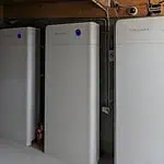 Three Sidenergy lithium battery units installed in basement or garage space with concrete block walls