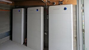 Three Sidenergy lithium battery units installed in basement or garage space with concrete block walls