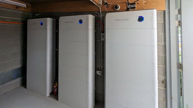 Three Sidenergy lithium battery units installed in basement or garage space with concrete block walls