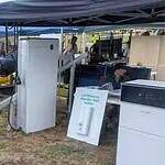 Trade show display featuring Sigenergy and Pylontech battery storage systems under outdoor tent with solar panels and attendees