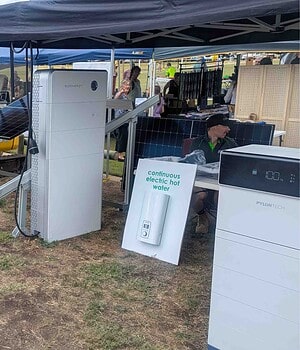 Trade show display featuring Sigenergy and Pylontech battery storage systems under outdoor tent with solar panels and attendees