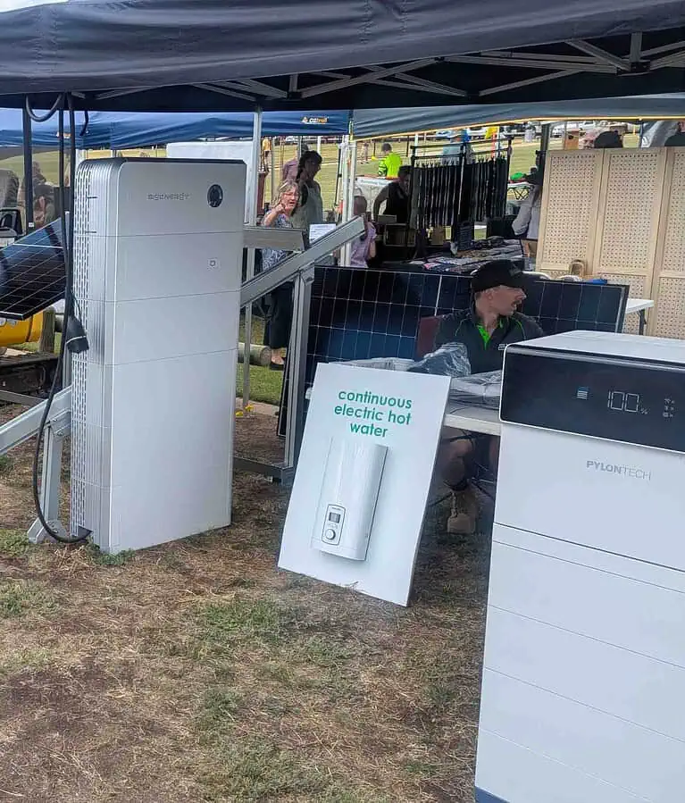 Trade show display featuring Sigenergy and Pylontech battery storage systems under outdoor tent with solar panels and attendees
