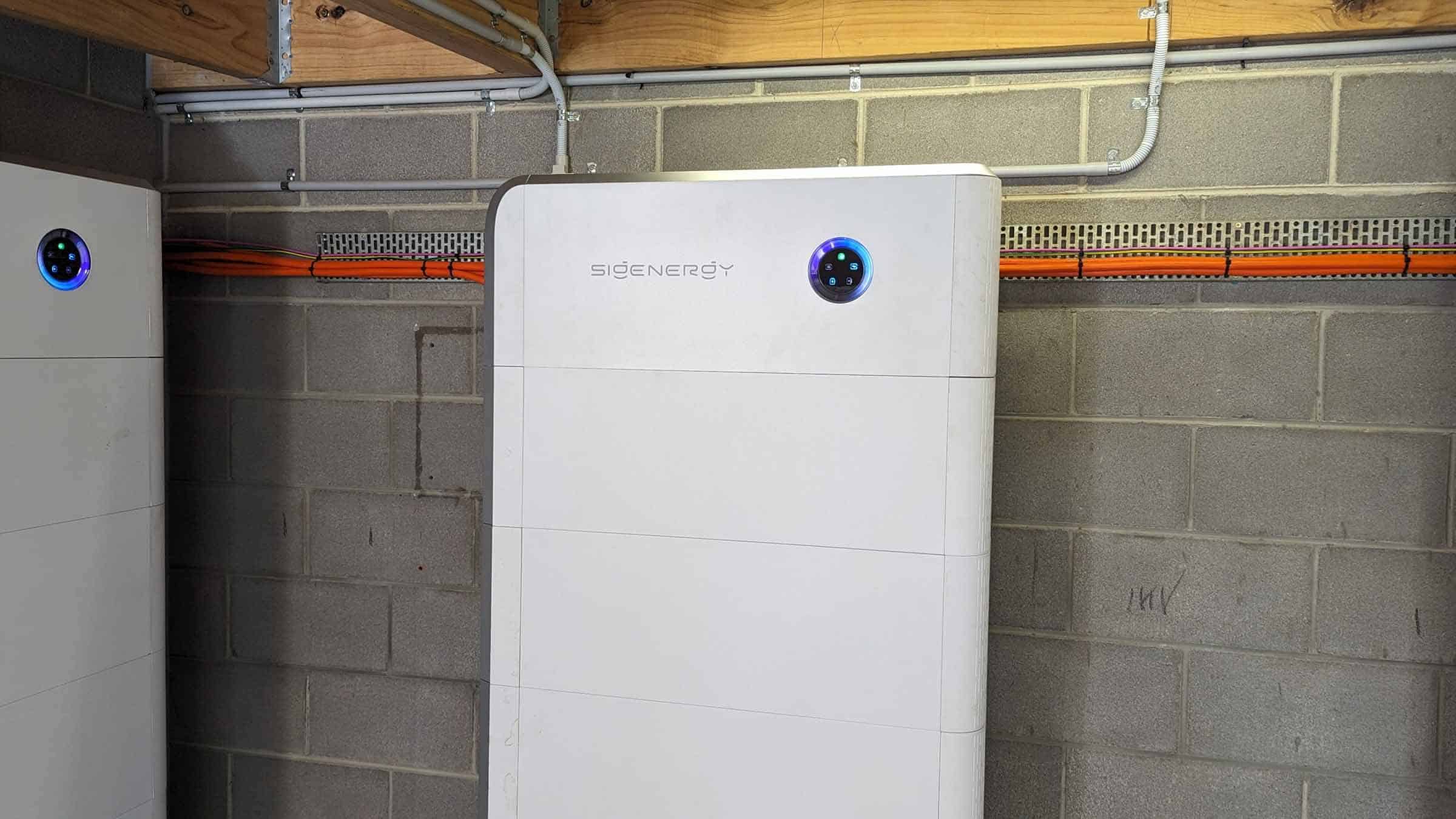 White SidEnergy battery unit mounted on basement wall with blue LED indicators showing system status