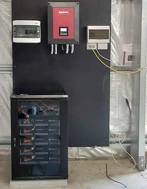 Ingeteam inverter mounted above Pylontech battery bank in black cabinet with monitoring equipment for off-grid solar system