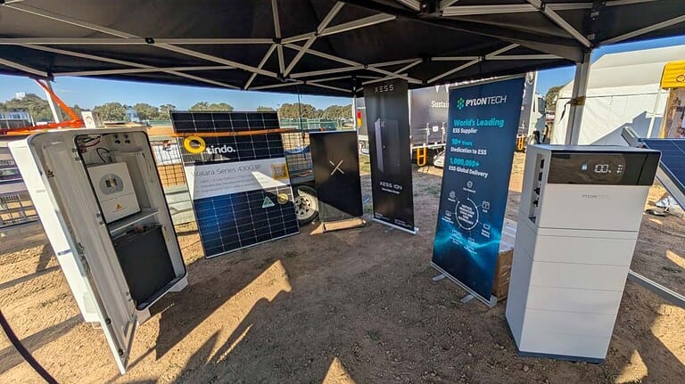Trade show display featuring Pylontech battery systems, solar panels, and energy storage equipment under marquee tent
