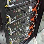 Four Pylontech US5000 lithium batteries mounted in server rack with orange high-voltage DC cables and management systems