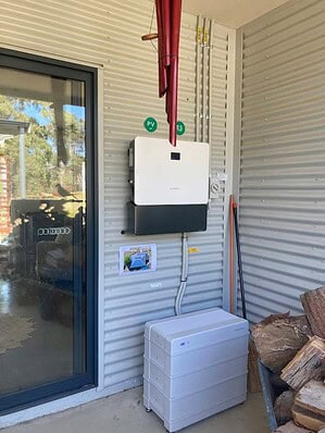Wall mounted solar inverter and stacked battery system installed beside house with clean cable management