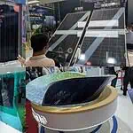 Trade show booth displaying curved solar panels and efficiency specifications at Chinese solar technology exhibition