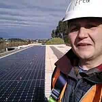 Solar technician in safety gear standing on large commercial rooftop solar panel installation in Ballarat