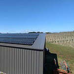 Solar panels covering the metal roof of a farm shed at Scotsburn winery, with vineyard rows visible in the background