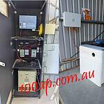 Side by side comparison of old Selectronic off-grid system with complex wiring and new white Sigenergy inverter in shed