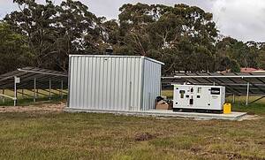 Off-grid solar installation with metal shed, Hyundai backup generator, and solar panel arrays in rural setting