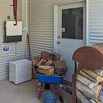 Off-grid solar system components including inverter, battery storage, and firewood pile on covered outdoor area in Queensland