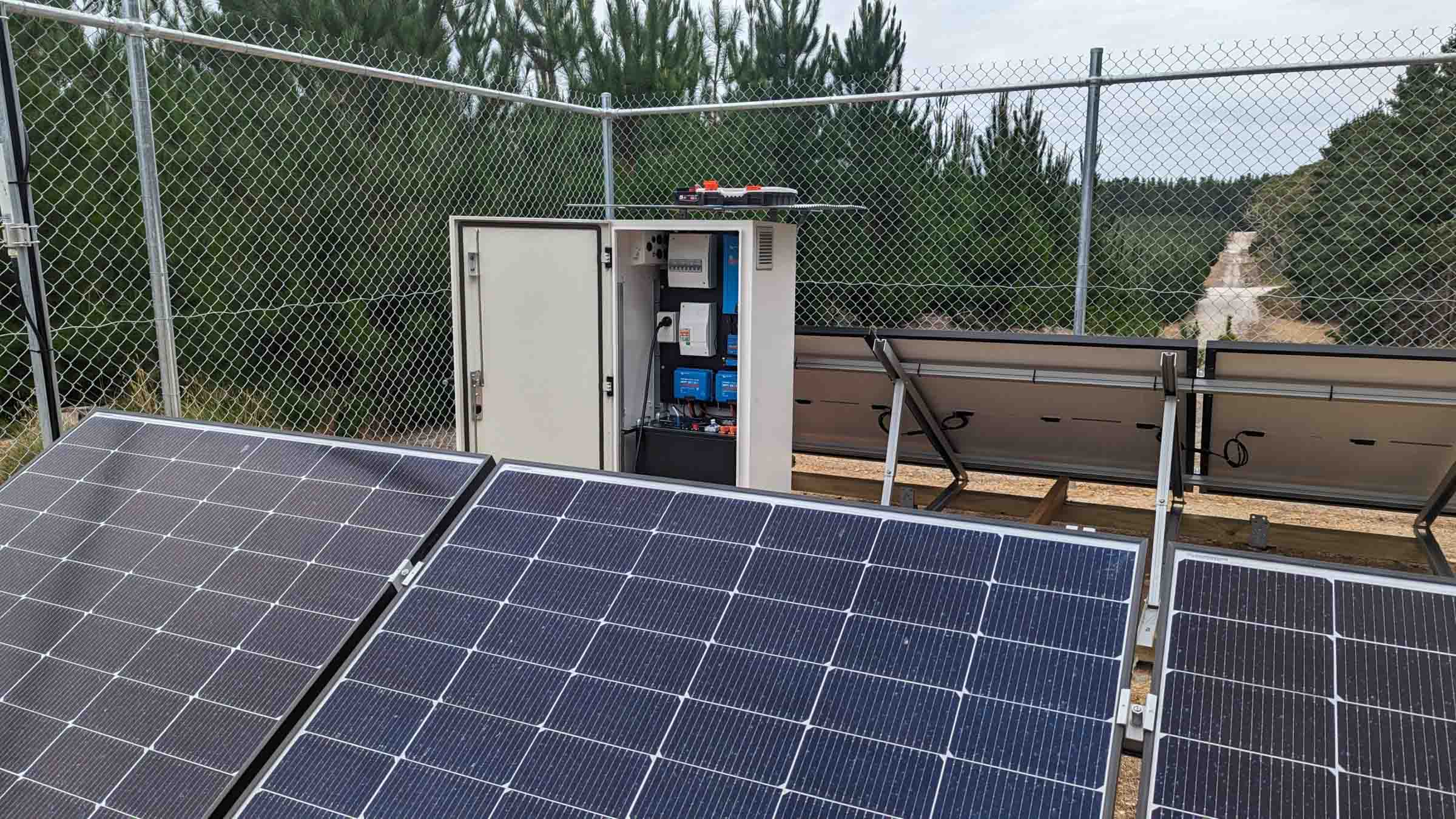 Solar panels and control cabinet behind security fencing at an off-grid installation in rural Victoria