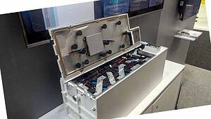 White lithium battery housing opened to show internal cell configuration with mounting brackets and wiring connections