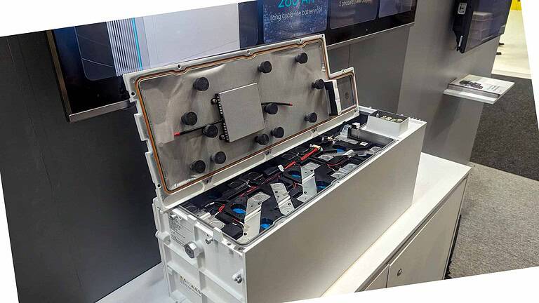 White lithium battery housing opened to show internal cell configuration with mounting brackets and wiring connections