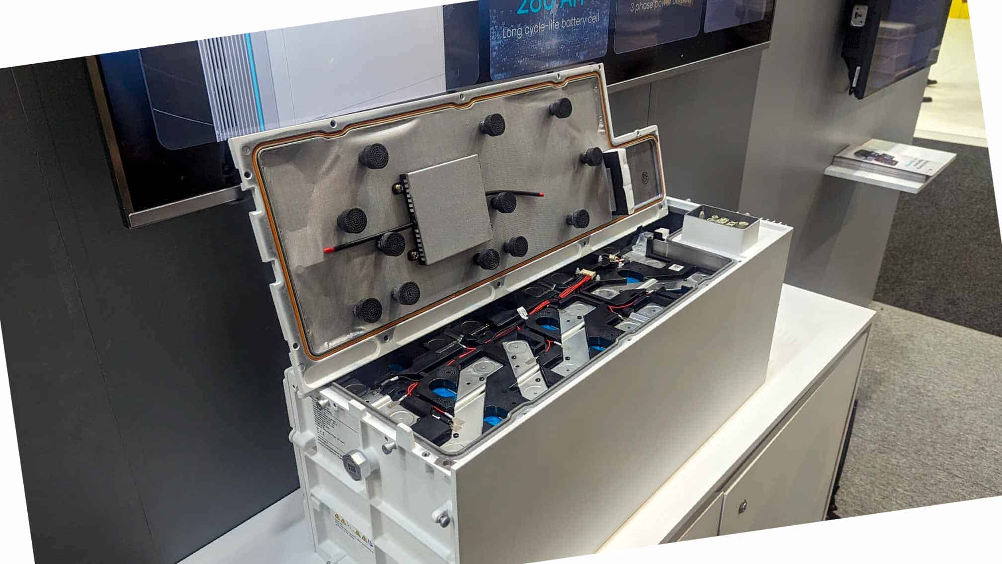 White lithium battery housing opened to show internal cell configuration with mounting brackets and wiring connections