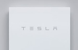 Tesla Powerwall home battery unit mounted on wall showing clean white design with Tesla branding
