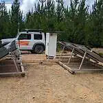 Solar panel ground mounting frames being assembled on cleared ground with installation vehicle and equipment box nearby