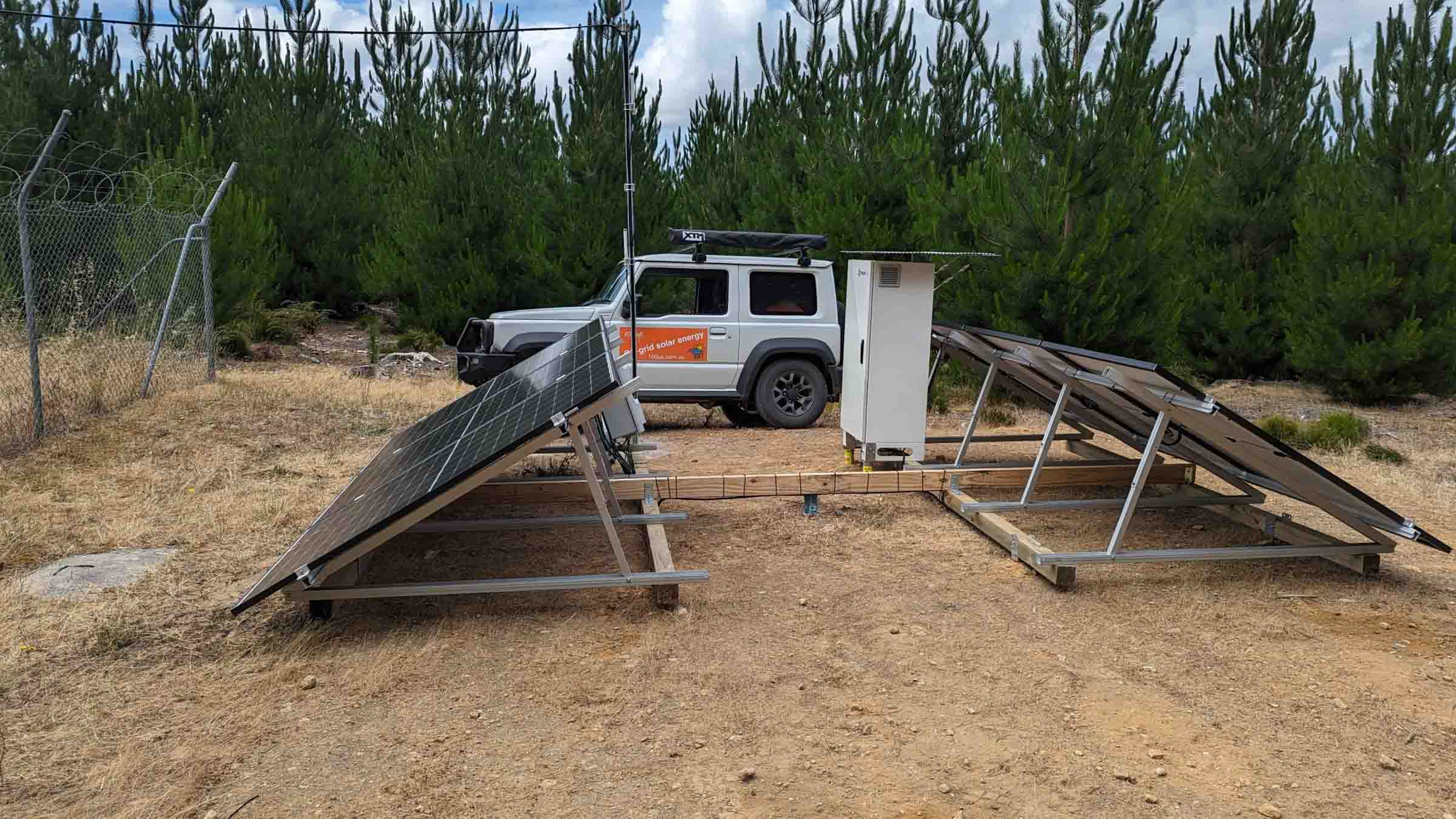 Solar panel ground mounting frames being assembled on cleared ground with installation vehicle and equipment box nearby