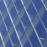 Diamond-pattern semi-transparent solar window panels installed on a building facade, allowing light through while generating power