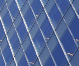 Diamond-pattern semi-transparent solar window panels installed on a building facade, allowing light through while generating power